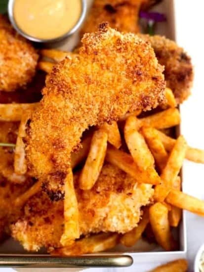 chicken tenders on a baking tray with fries