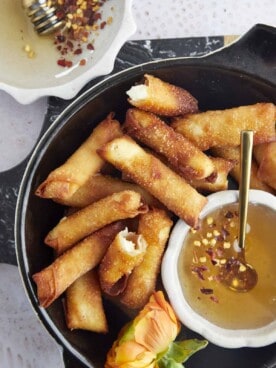 a basket of fried feta rolls with a bowl of hot honey