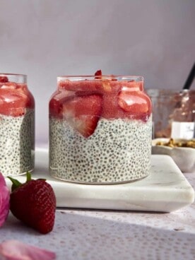 Side view of a jar of strawberry chia pudding topped with strawberry puree and strawberry slices.