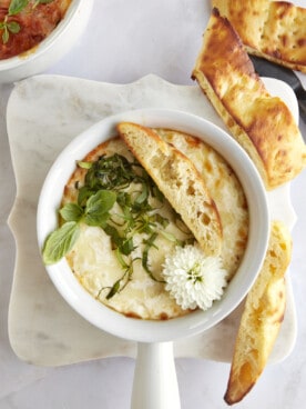 Overhead image of a ramekin of Eggs in Purgatory with a piece of bread on top.