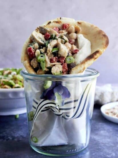 Pita bread stuffed with chickpea chicken salad wrapped and stood upright in a jar.