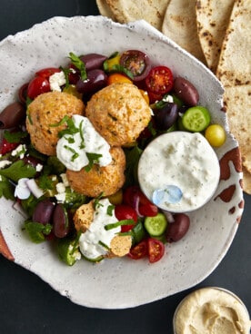 A bowl of chicken shawarma meatballs with veggies and tzatziki.