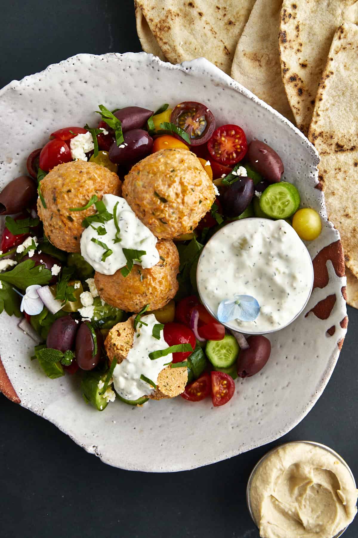 A bowl of chicken shawarma meatballs with veggies and tzatziki.