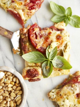 A slice of tomato pesto puff pastry topped with fresh basil.