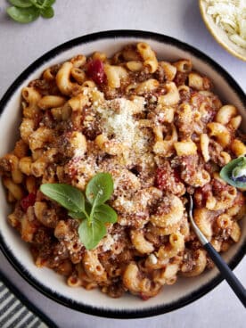 A bowl of ground beef pasta topped with grated Parmesan and fresh Parsley.