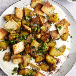 Harissa potatoes over whipped tahini sauce topped with fried pita.