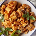 A plate of spicy chicken rigatoni topped with fresh herbs and cheese.