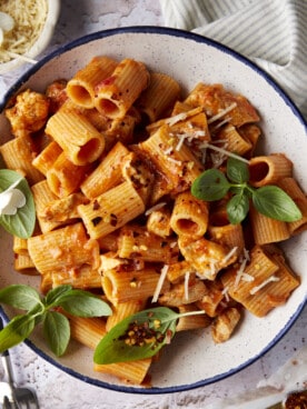 A plate of spicy chicken rigatoni topped with fresh herbs and cheese.