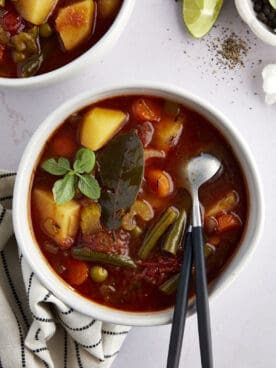 A bowl of slow cooker vegetable soup with two spoons sticking out.