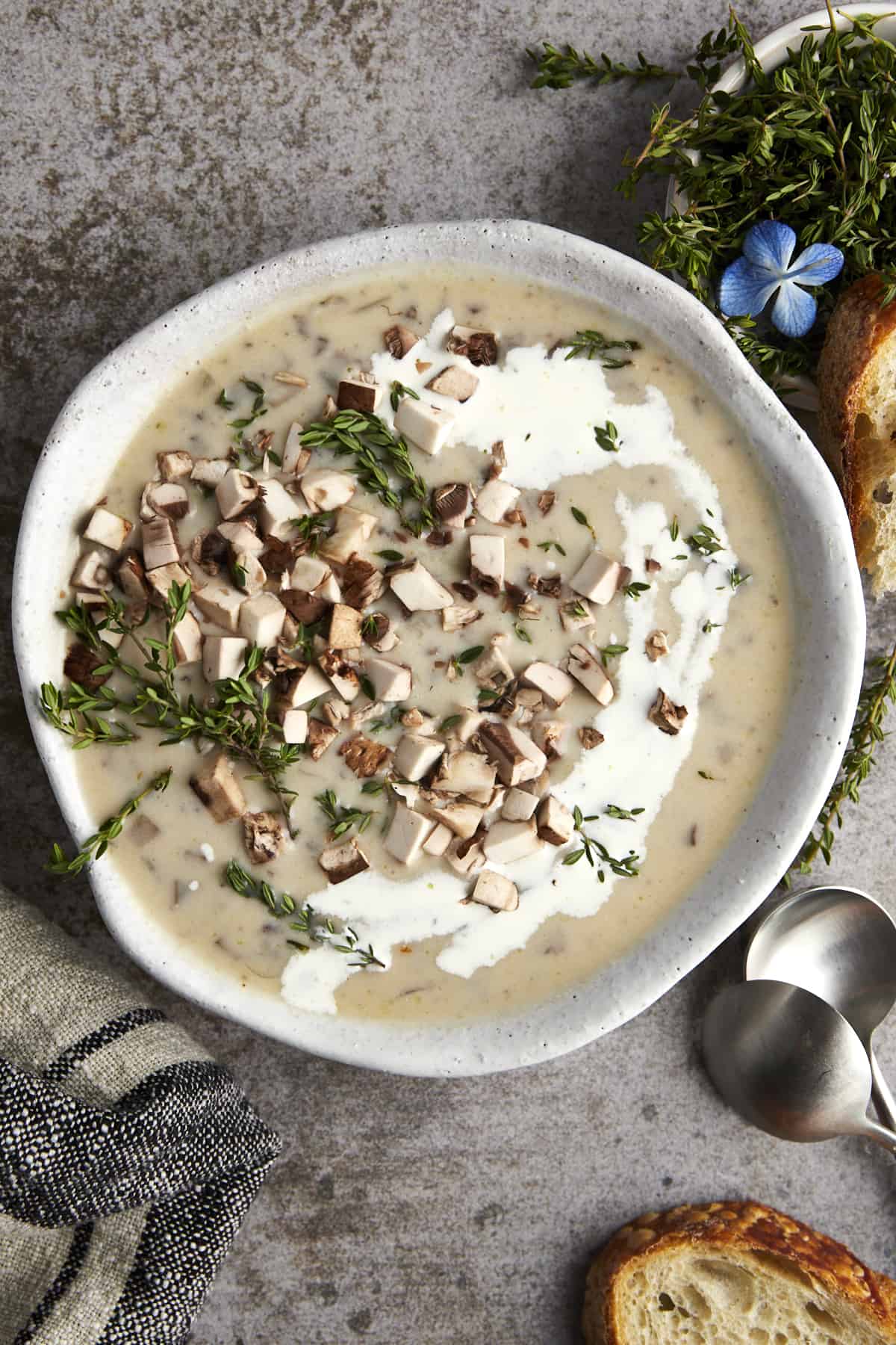 A bowl of creamy mushroom soup topped with mushrooms and thyme.