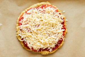 A chicken crust pizza topped with marinara, tomatoes, and cheese.