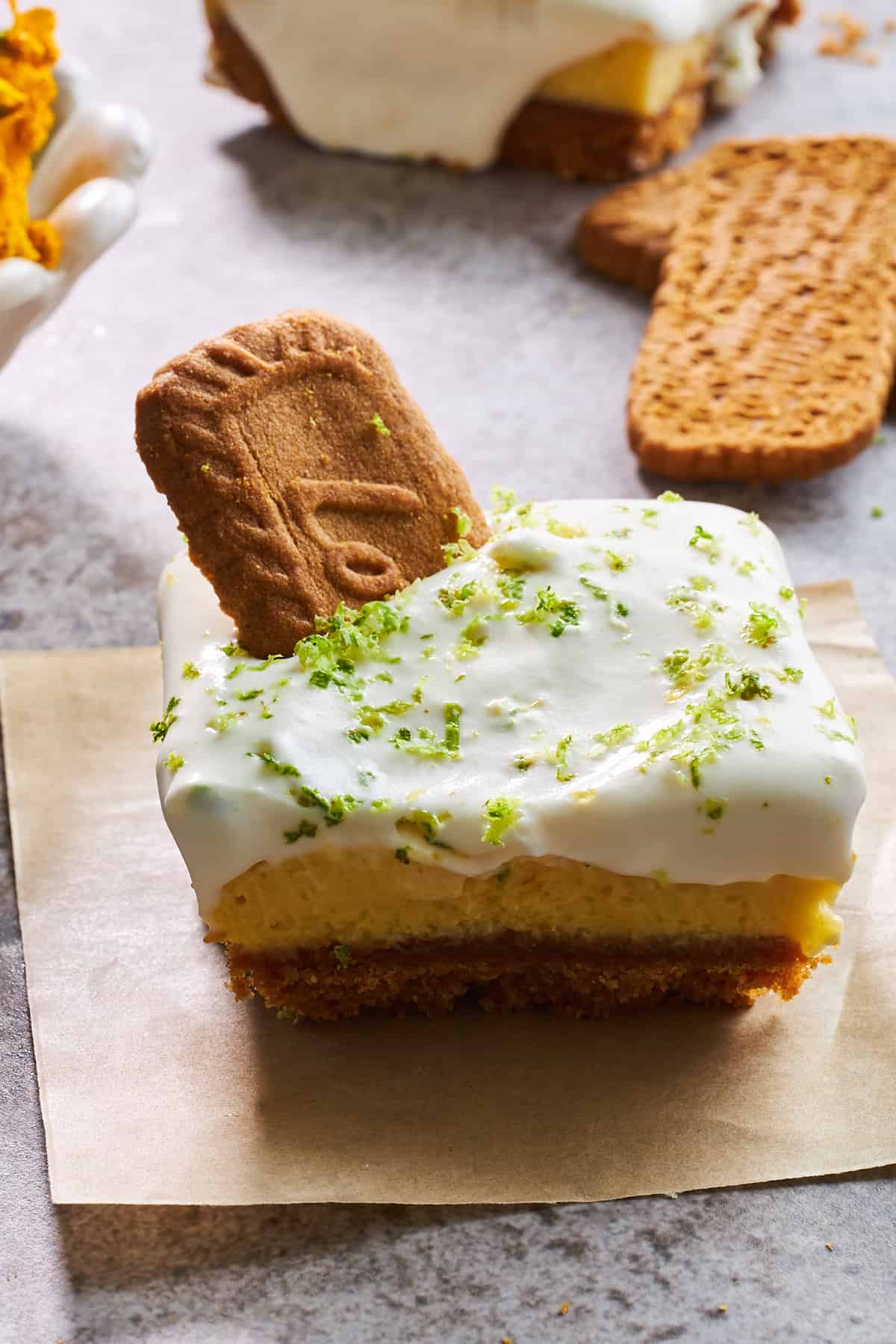 A three layer key lime pie bar topped with a Biscoff cookie. 