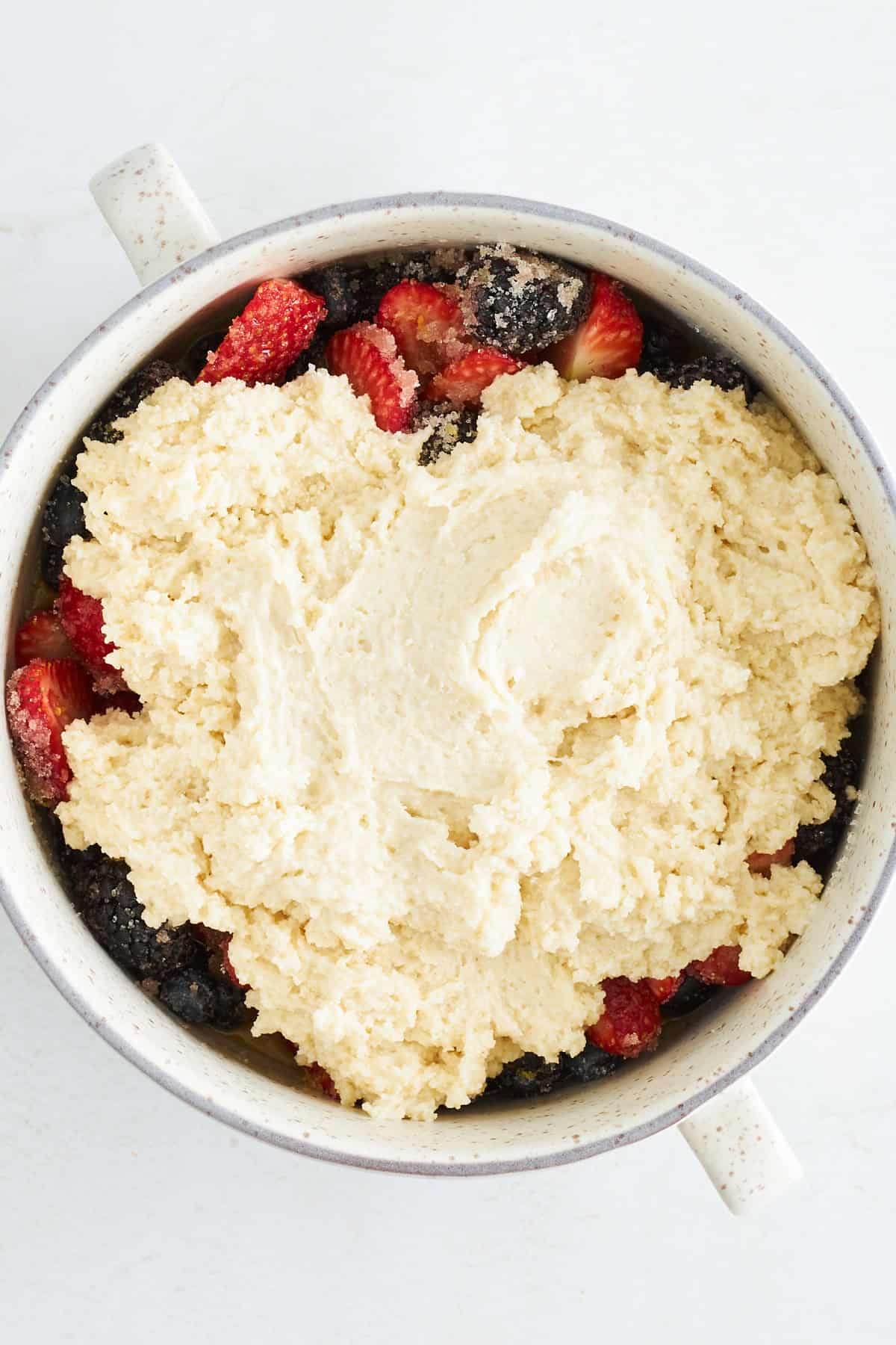 Uncooked mixed berry cobbler in a round baking dish. 