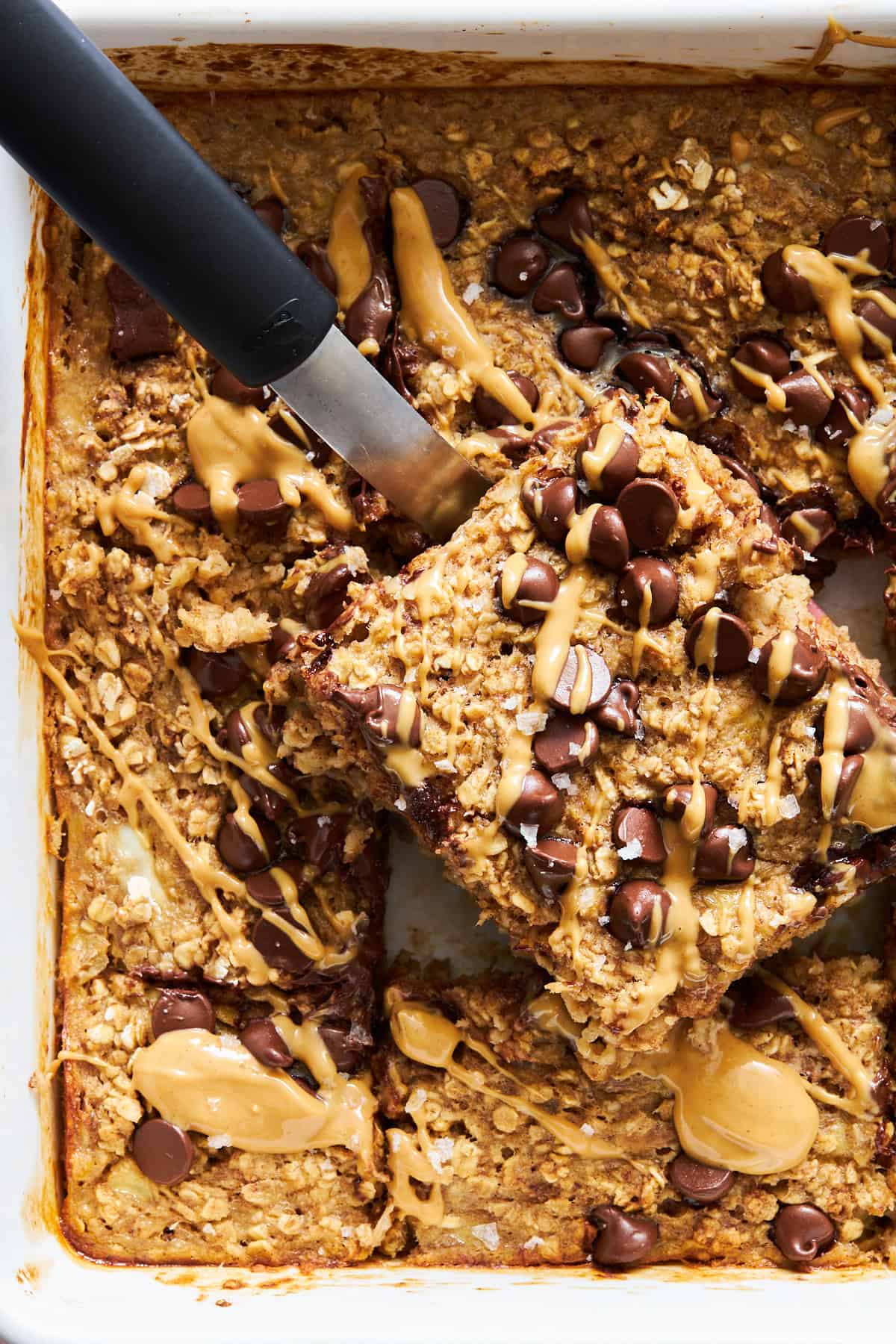 A peanut butter oatmeal bar being lifted from a baking dish.