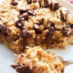 A peanut butter oatmeal bar on a plate with a fork holding a bite.