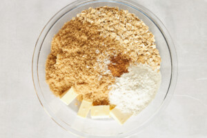 Flour, oats, brown sugar, cinnamon, and butter in a mixing bowl.