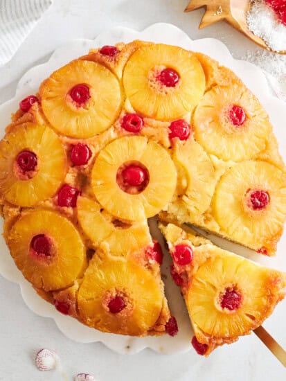 Overhead image of a pineapple upside down cake with a slice being removed.