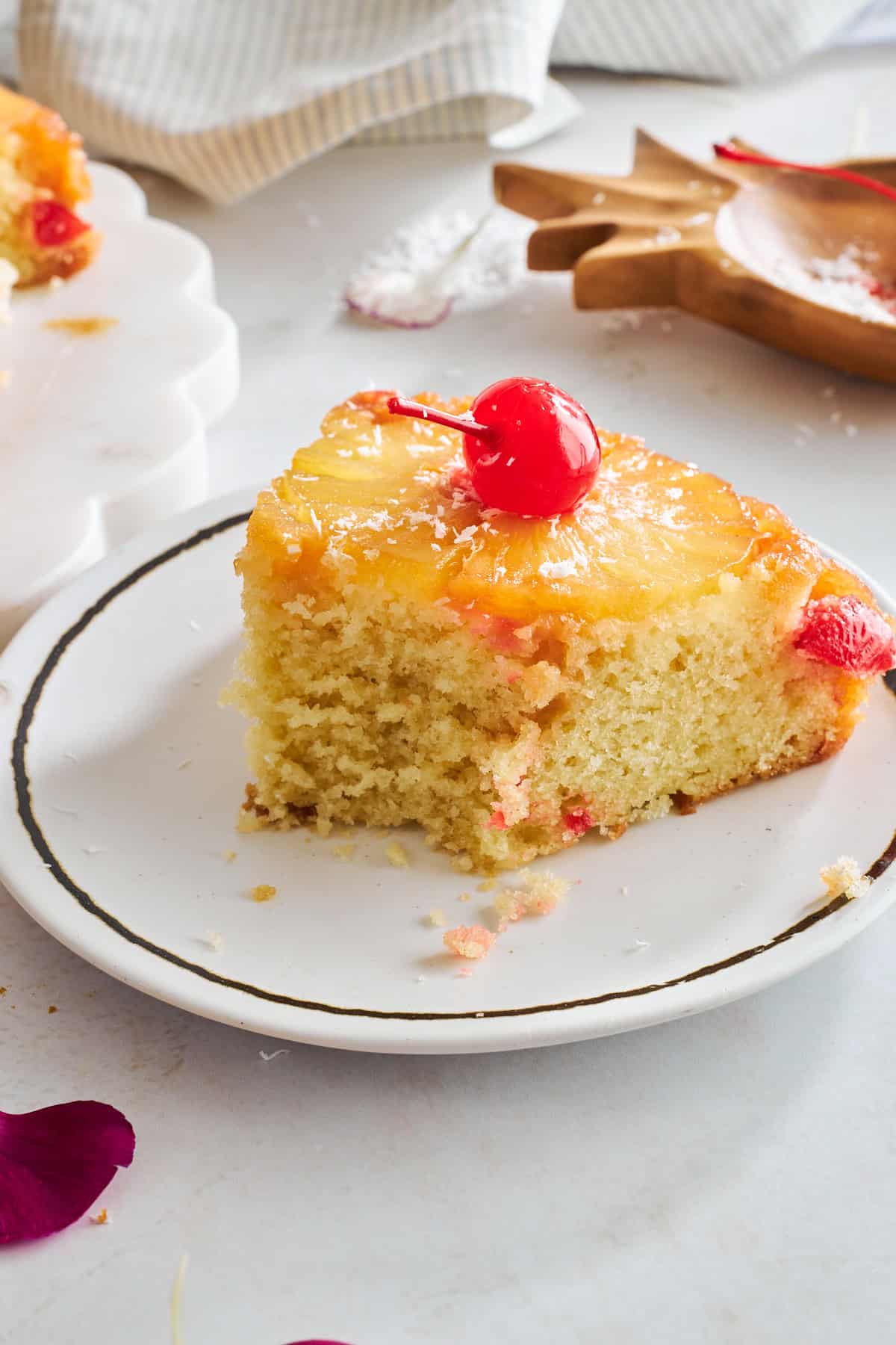 A slice of pineapple upside down cake on a plate with a bite missing. 