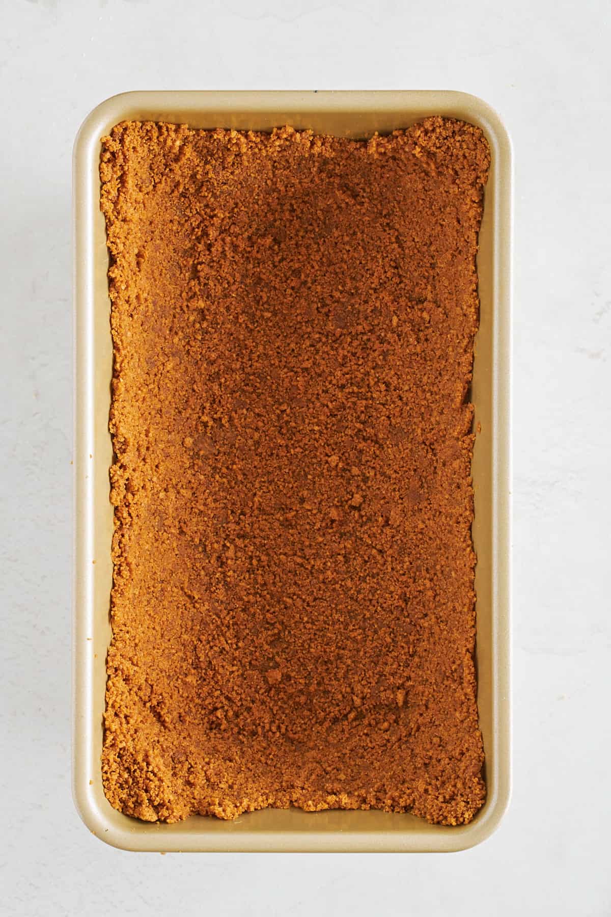 Biscoff cookie crust pressed into a loaf pan. 