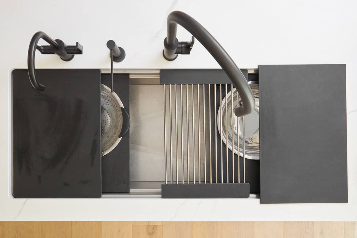 Overhead image of a kitchen sink with various attachments for cutting boards and wire racks. 