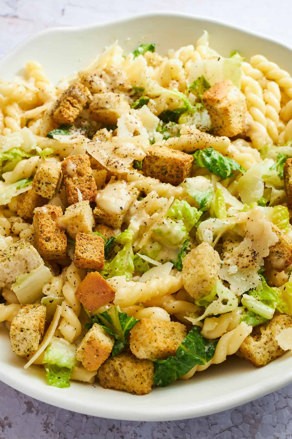 Close up image of a bowl of Caesar pasta salad. 