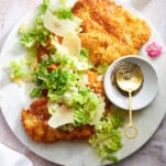 A plate of chicken Milanese topped with Caesar salad.