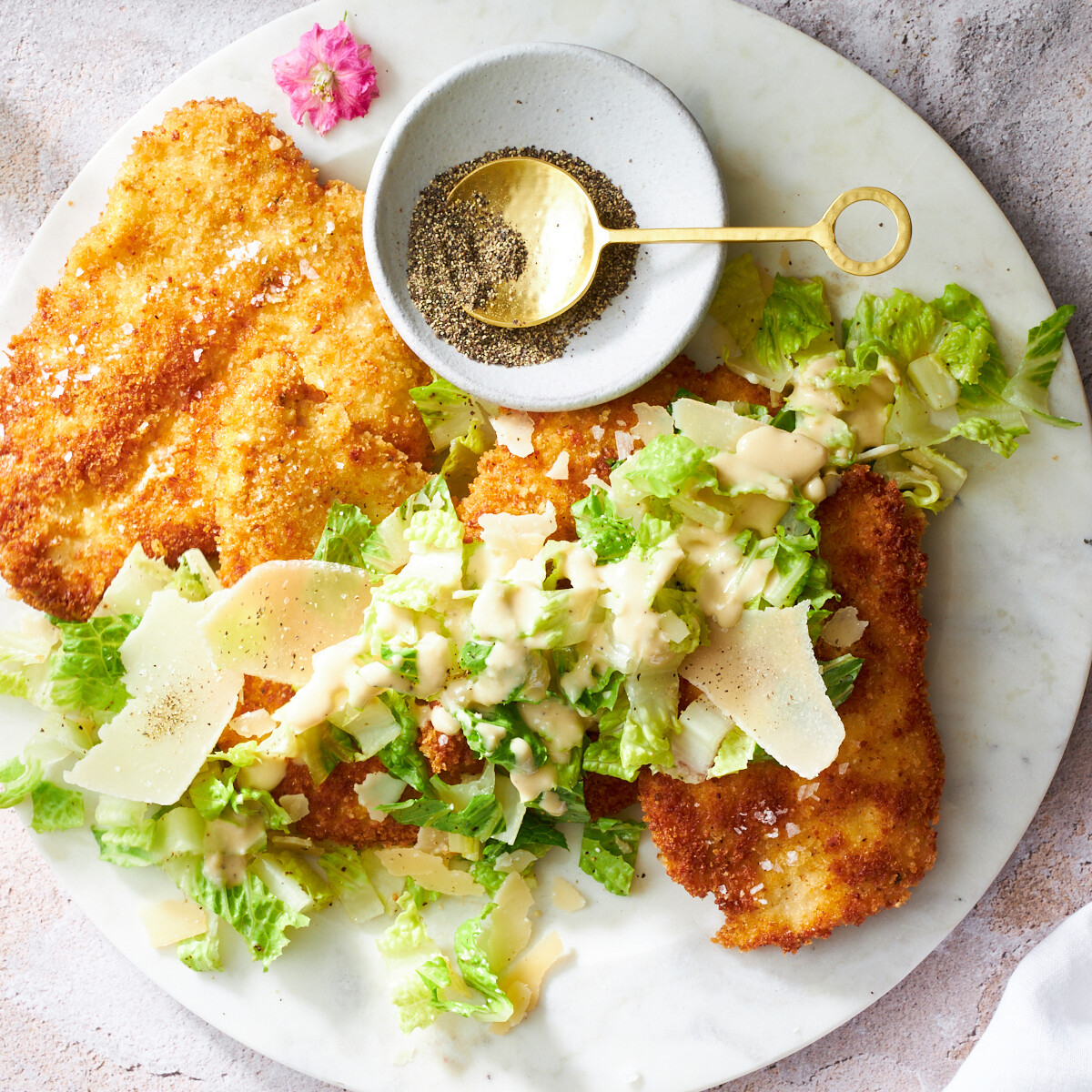 A plate of chicken Milanese topped with Caesar salad.