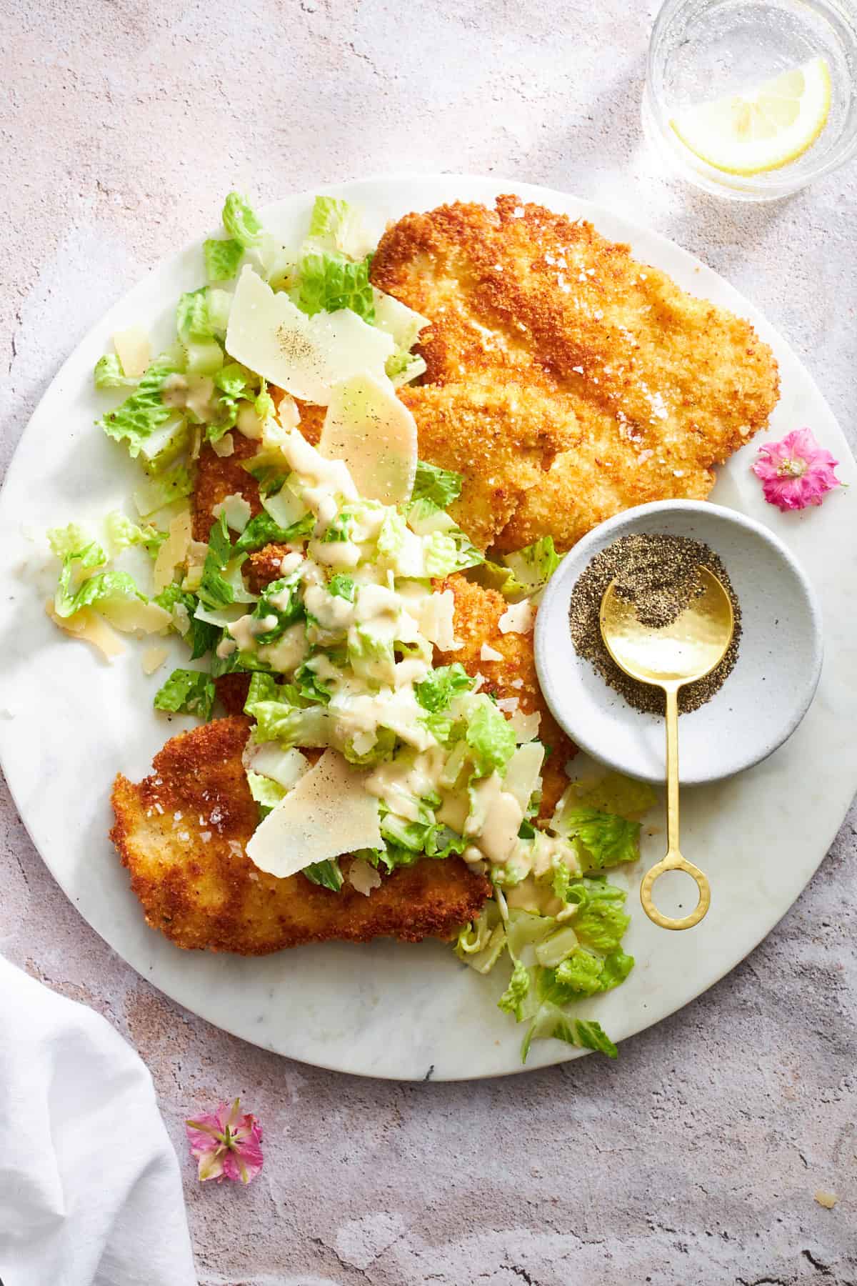 A plate of chicken Milanese topped with Caesar salad. 