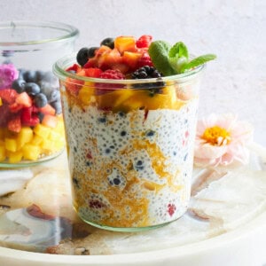 A jar of mango chia pudding topped with fruit salad.