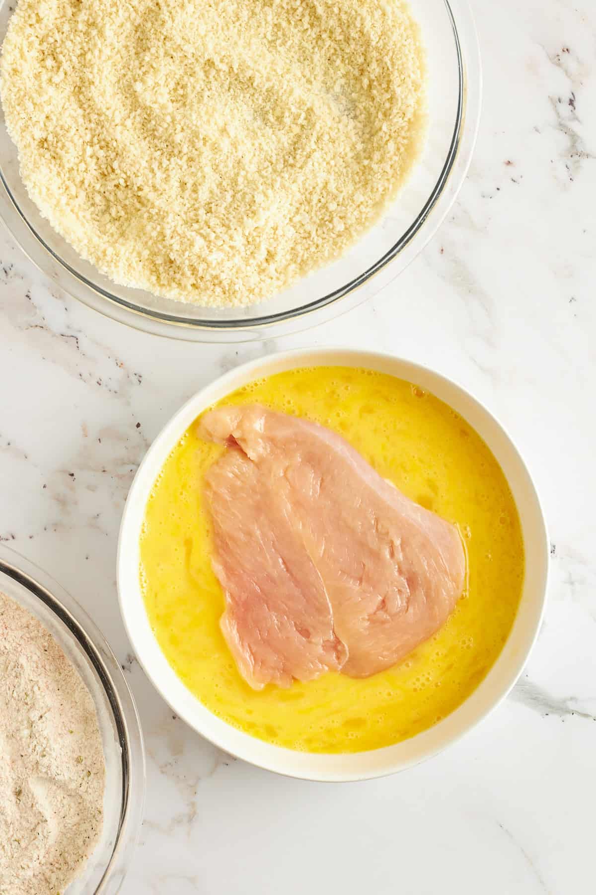 Raw chicken in a bowl of whisked eggs.
