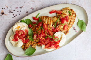 A platter of tomato basil chicken with burrata.