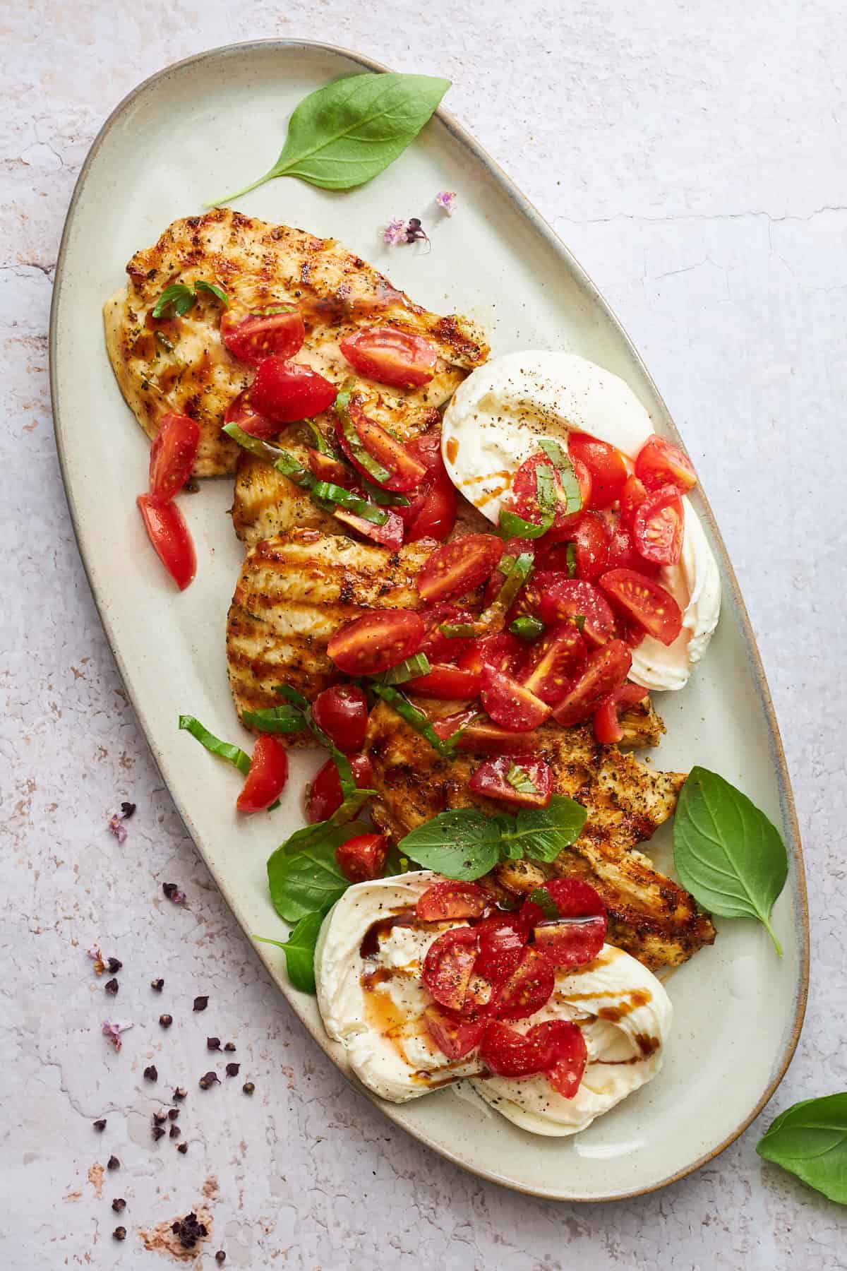 Tomato basil chicken with burrata on a platter.