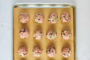 Raw beef meatballs on a baking sheet.