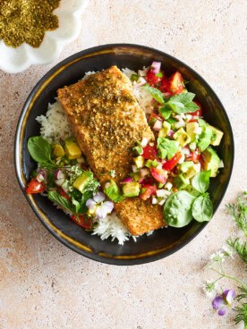 A bowl of white rice with baked salmon and avocado salsa.