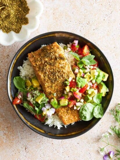 A bowl of white rice with baked salmon and avocado salsa.