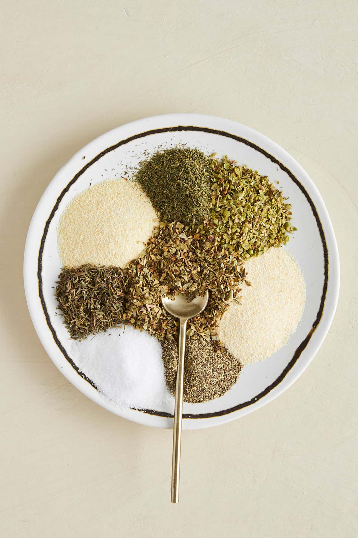 Greek seasoning ingredients on a plate with a spoon on top. 