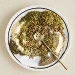 A plate of Greek seasoning ingredients with a spoon on top.