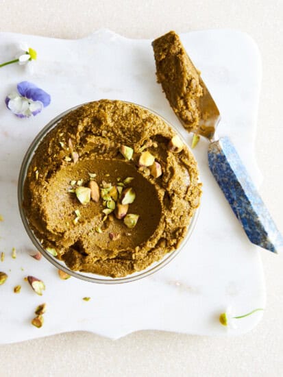 Overhead image of a jar of pistachio butter with a knife on the side.