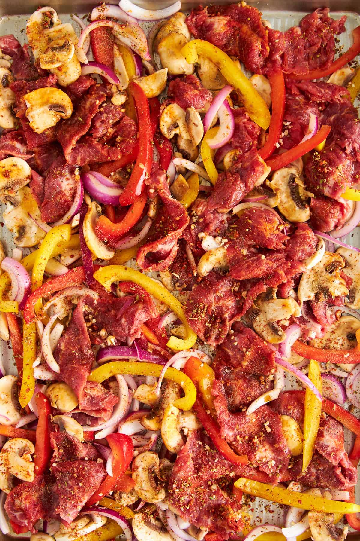 Uncooked Philly cheesesteak ingredients on a baking sheet. 