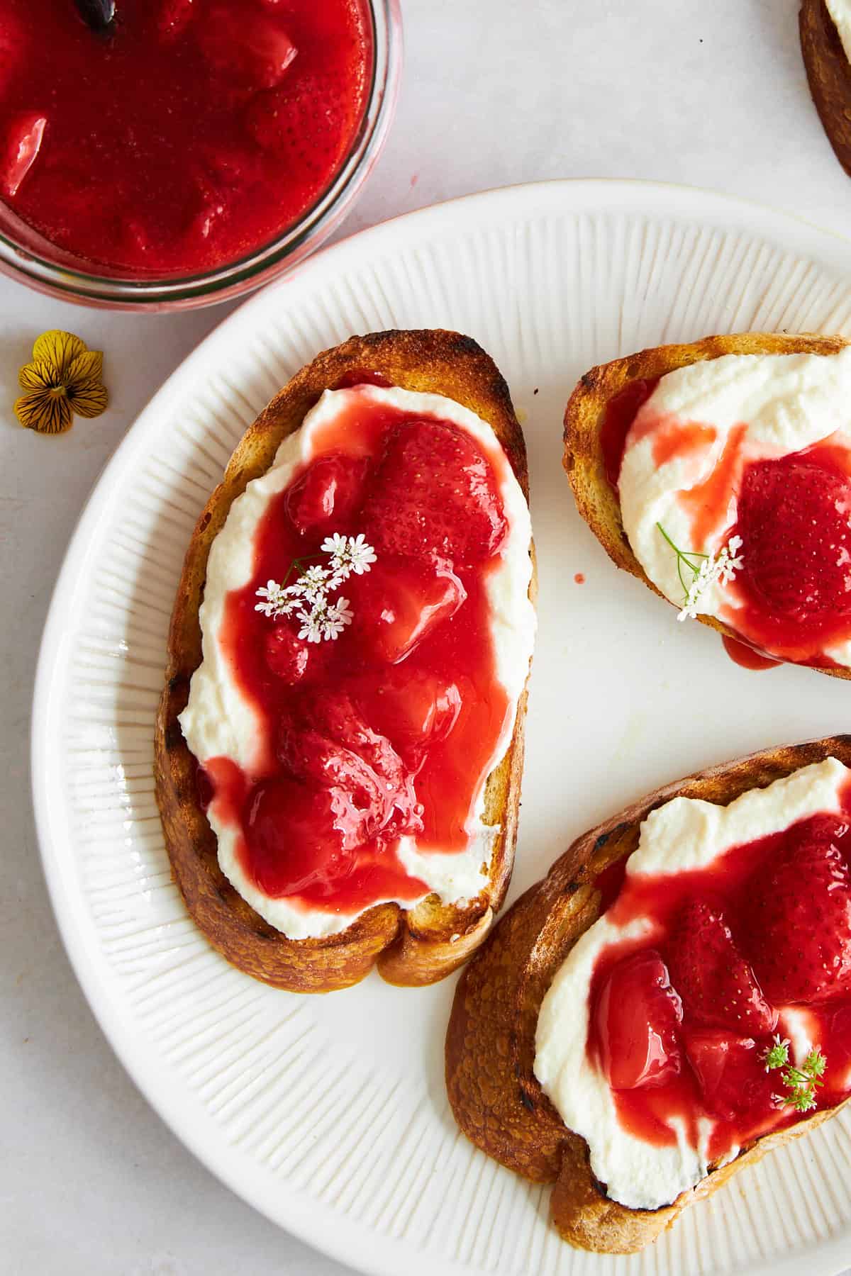 Pieces of strawberry ricotta toast on a plate. 