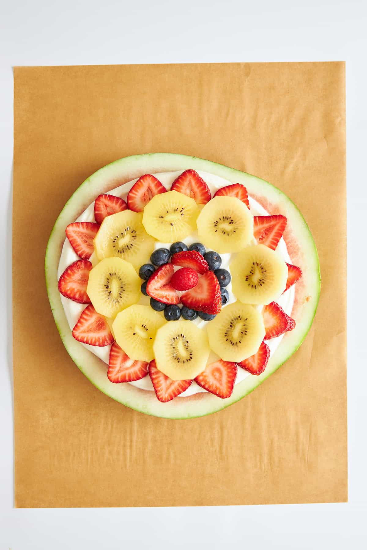 Watermelon pizza topped with yogurt, strawberries, kiwi, and blueberries. 