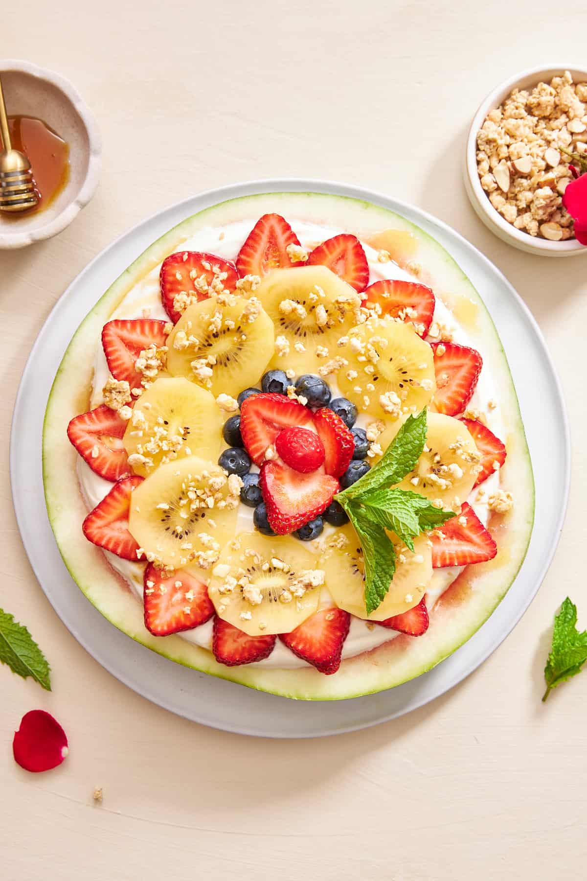 Watermelon pizza topped with yogurt, fruit, granola, and mint. 