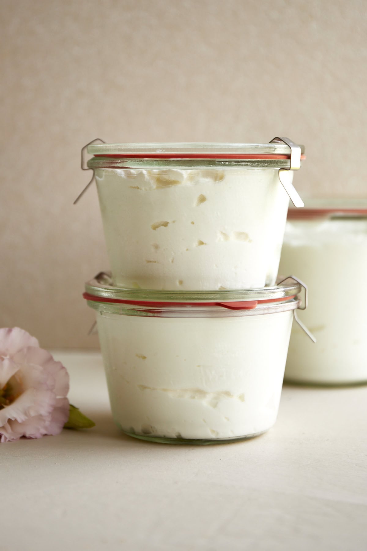 Two glass Weck jars full of homemade Greek yogurt stacked on top of each other.