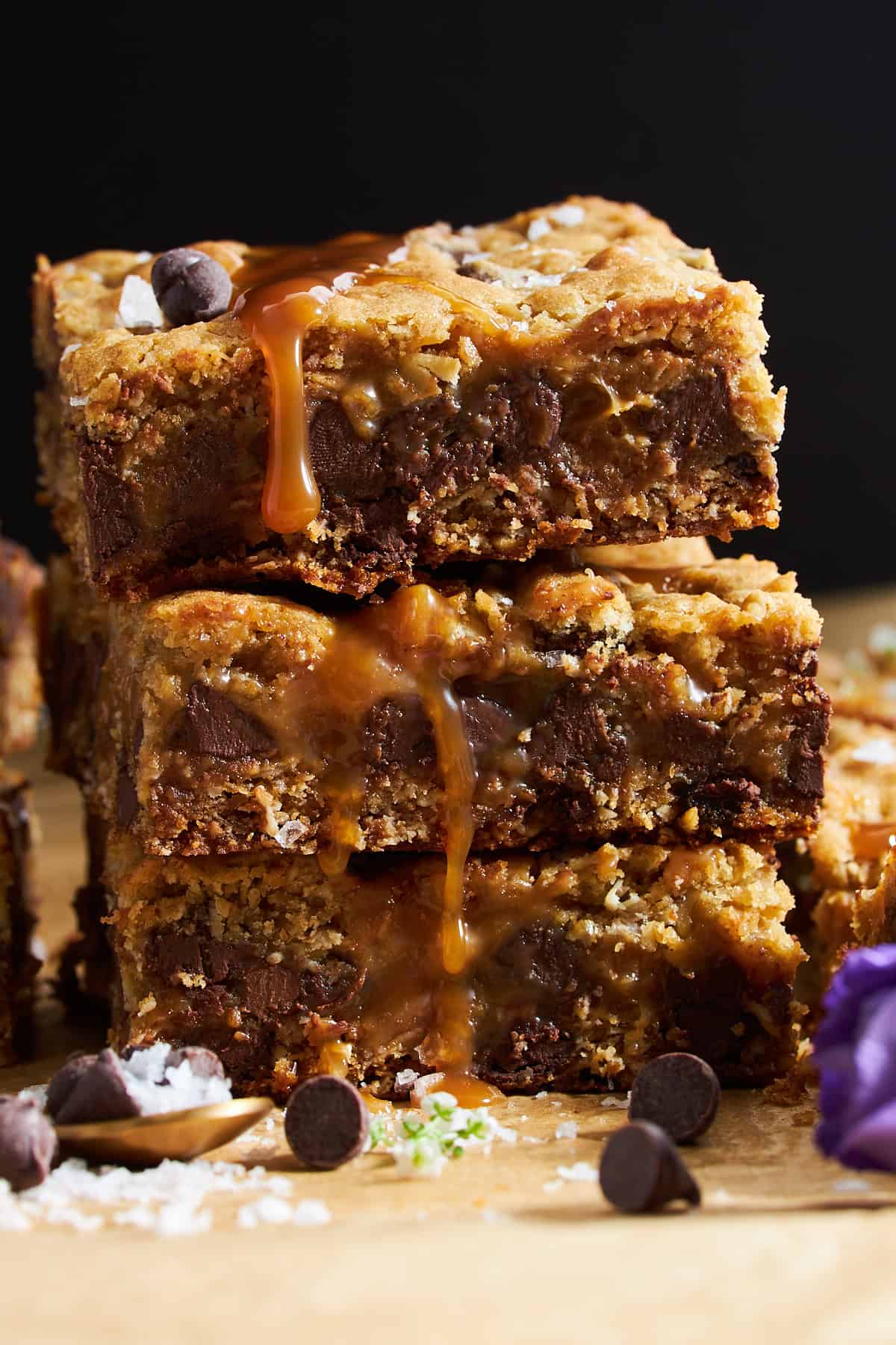 Three chocolate chip caramel bars stacked on top of each other. 