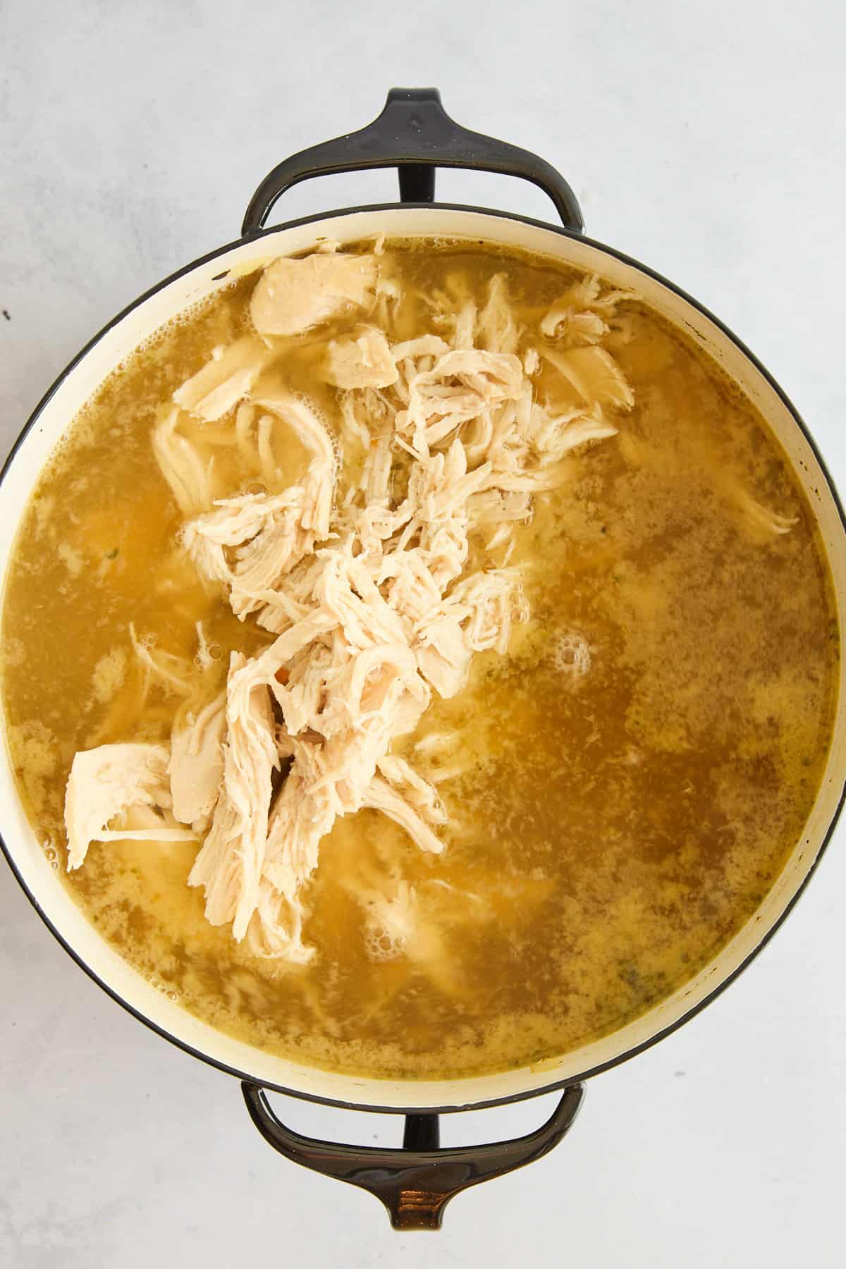 Shredded chicken floating in broht. 