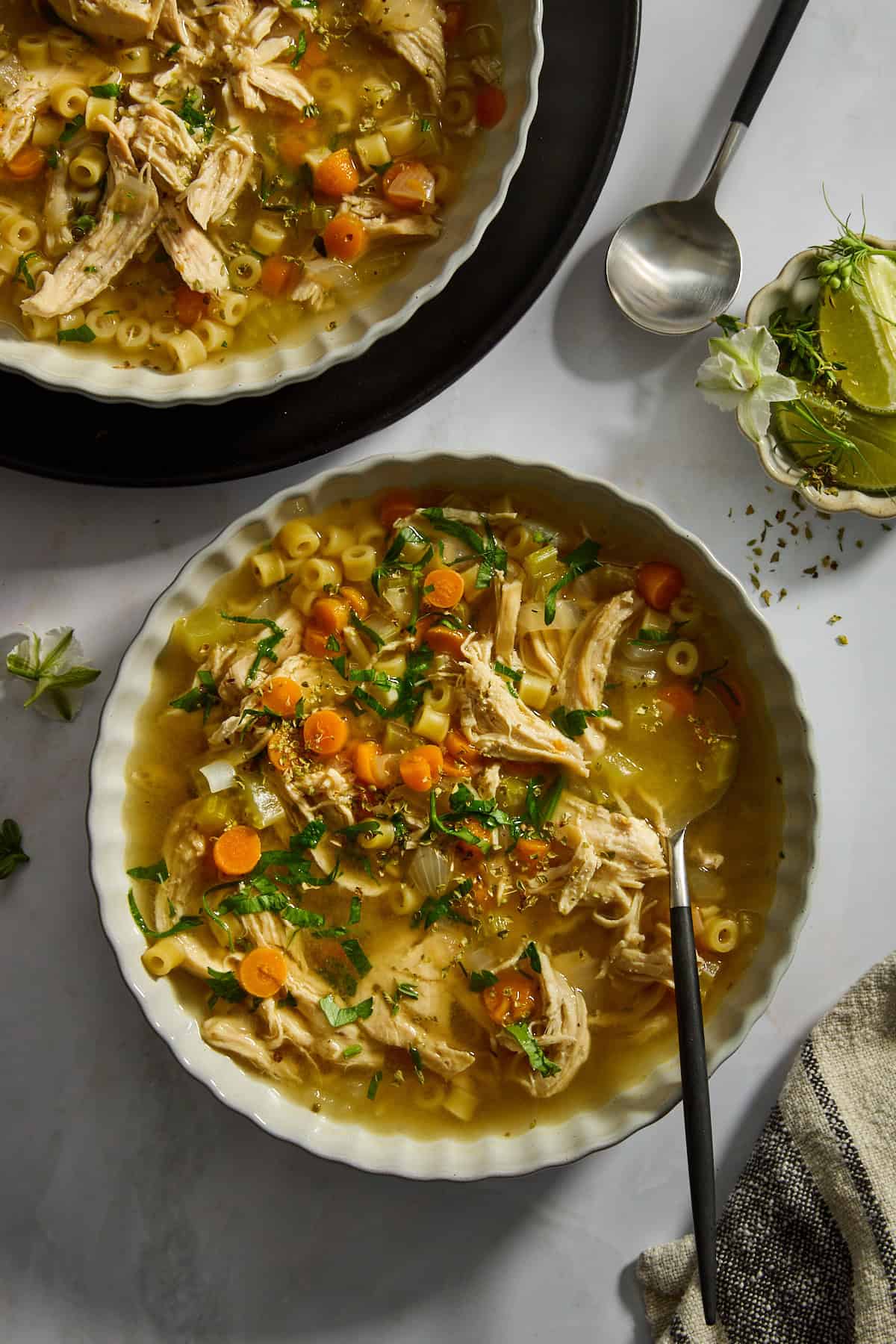 A bowl of homemade chicken noodle soup with a spoon sticking out. 