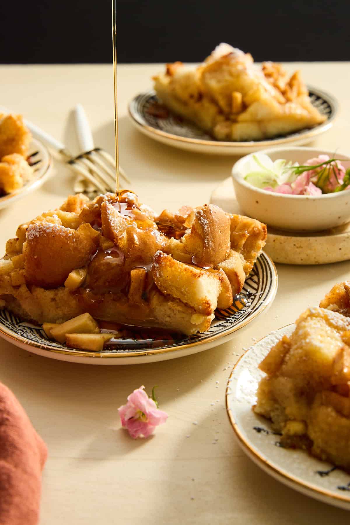 Syrup being drizzled over a serving of apple cinnamon french toast on a plate. 