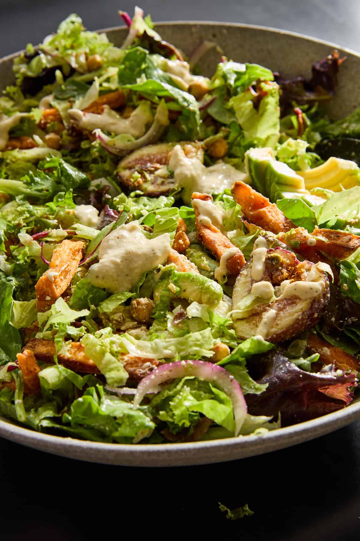 Close up view of a Roasted Carrots Chickpea Fig Salad topped with dressing. 