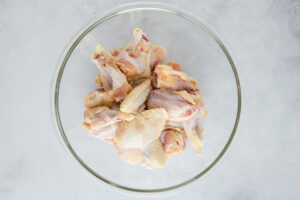 Raw chicken wings in a glass bowl.