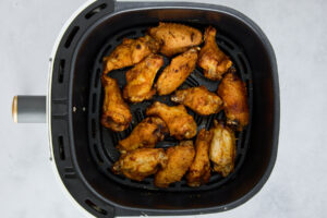 Cooked parmesan garlic chicken wings in an air fryer basket.